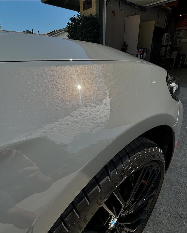 A gray car with black wheels is parked in a garage