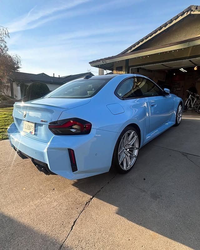 A blue bmw m4 is parked in a driveway in front of a house.