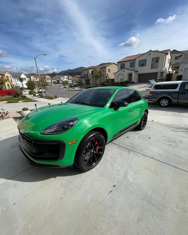 A green porsche macan gts is parked in a driveway.