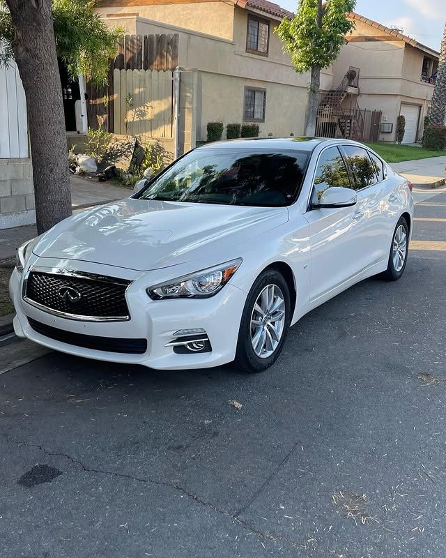 A white car is parked on the side of the road next to a tree.