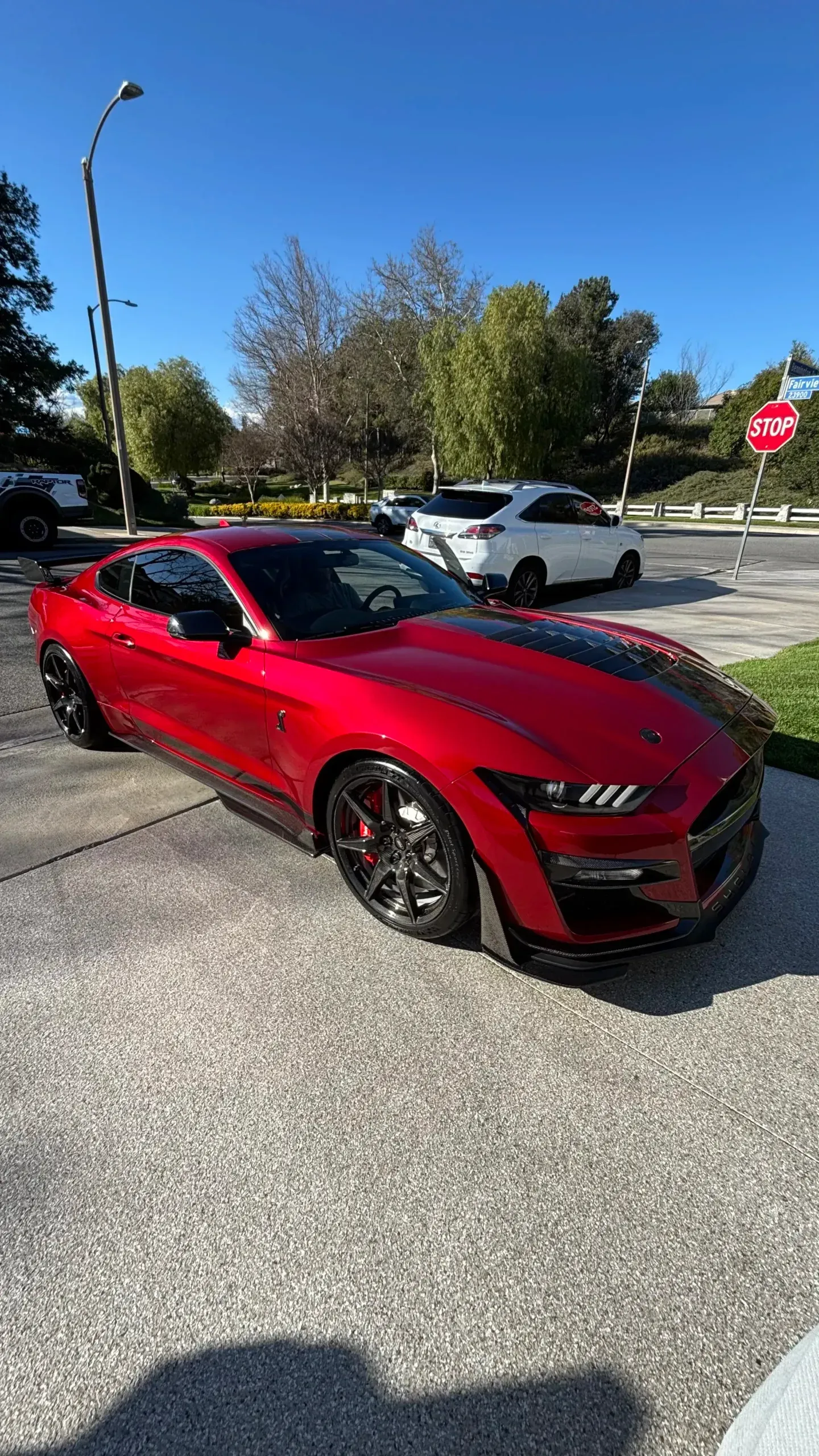 A red mustang is parked in a driveway next to a stop sign.