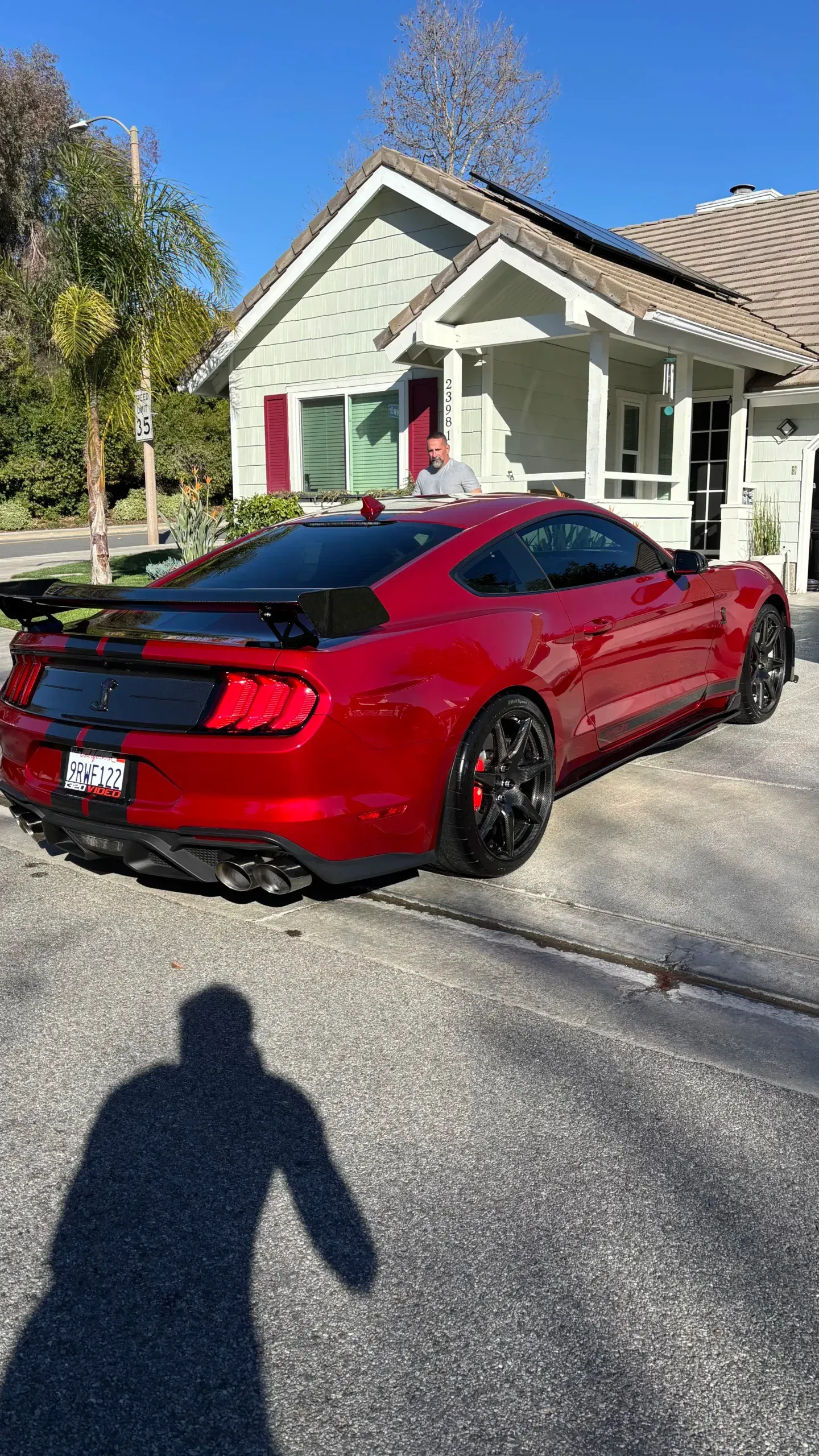 A red mustang is parked in front of a house.