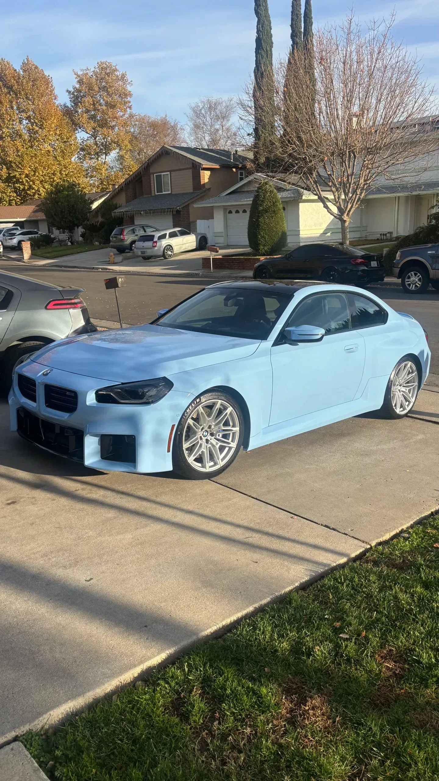 A blue bmw is parked in a driveway next to a house.