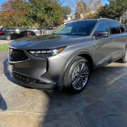 A gray acura mdx is parked in a parking lot.