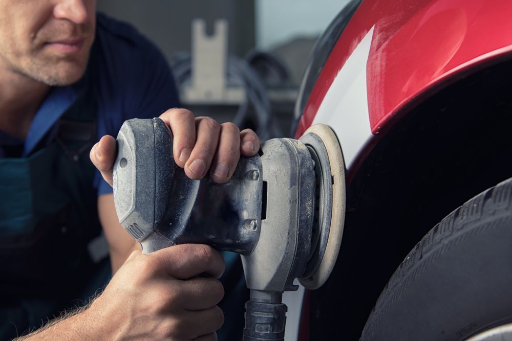A man is polishing a car with a machine.