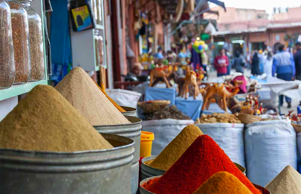 View along a display of spices at an outdoor market in a wide street