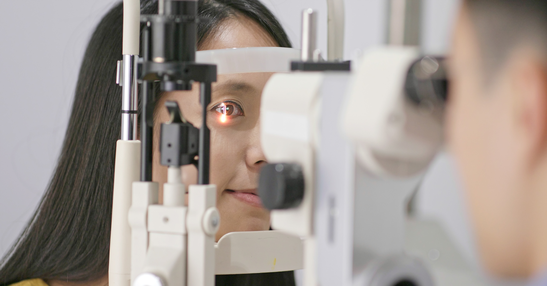 Woman undergoing eye exam with slit lamp by eye doctor.