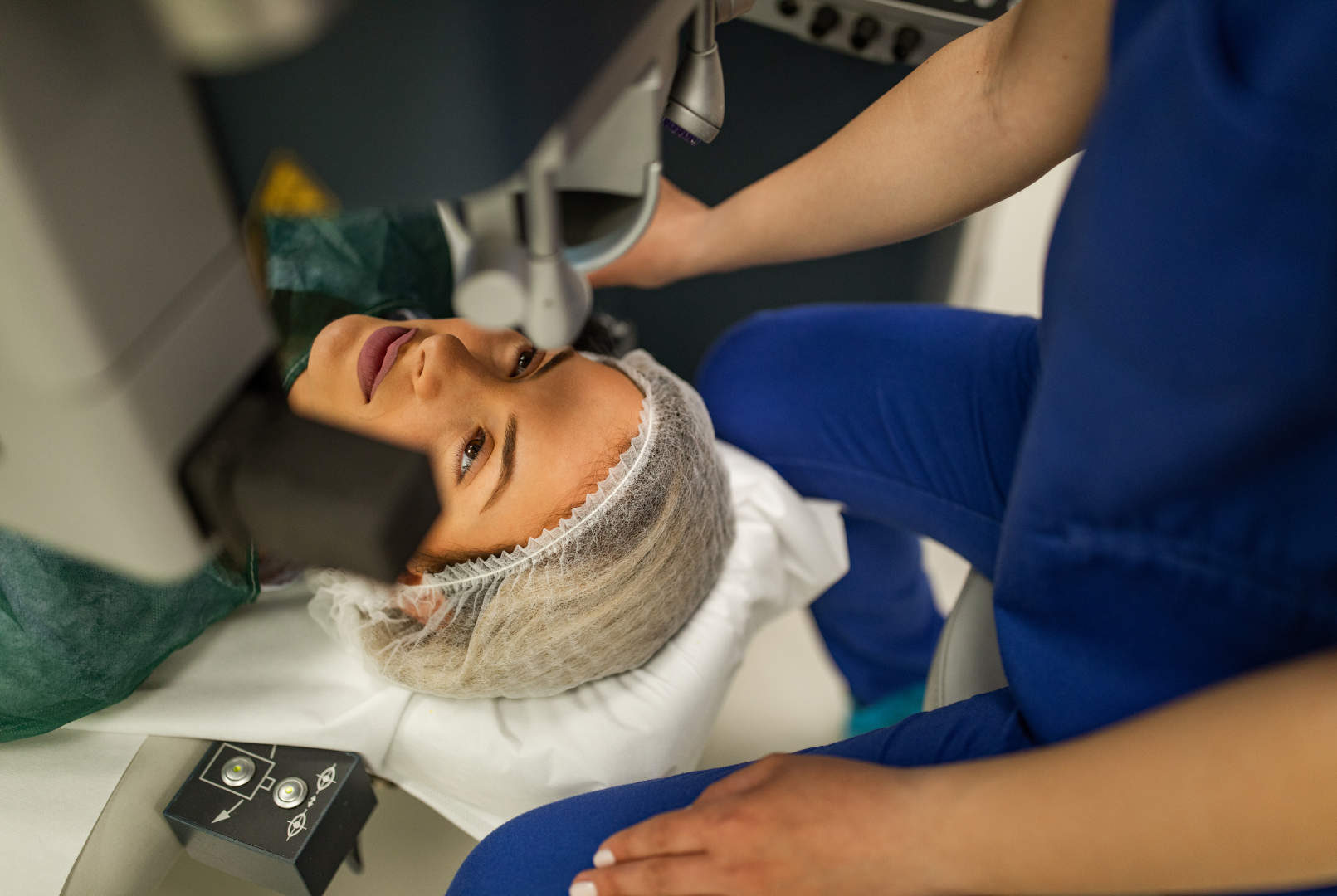 Woman undergoing laser eye surgery, lying down, looking up, with medical equipment focused on her eye.