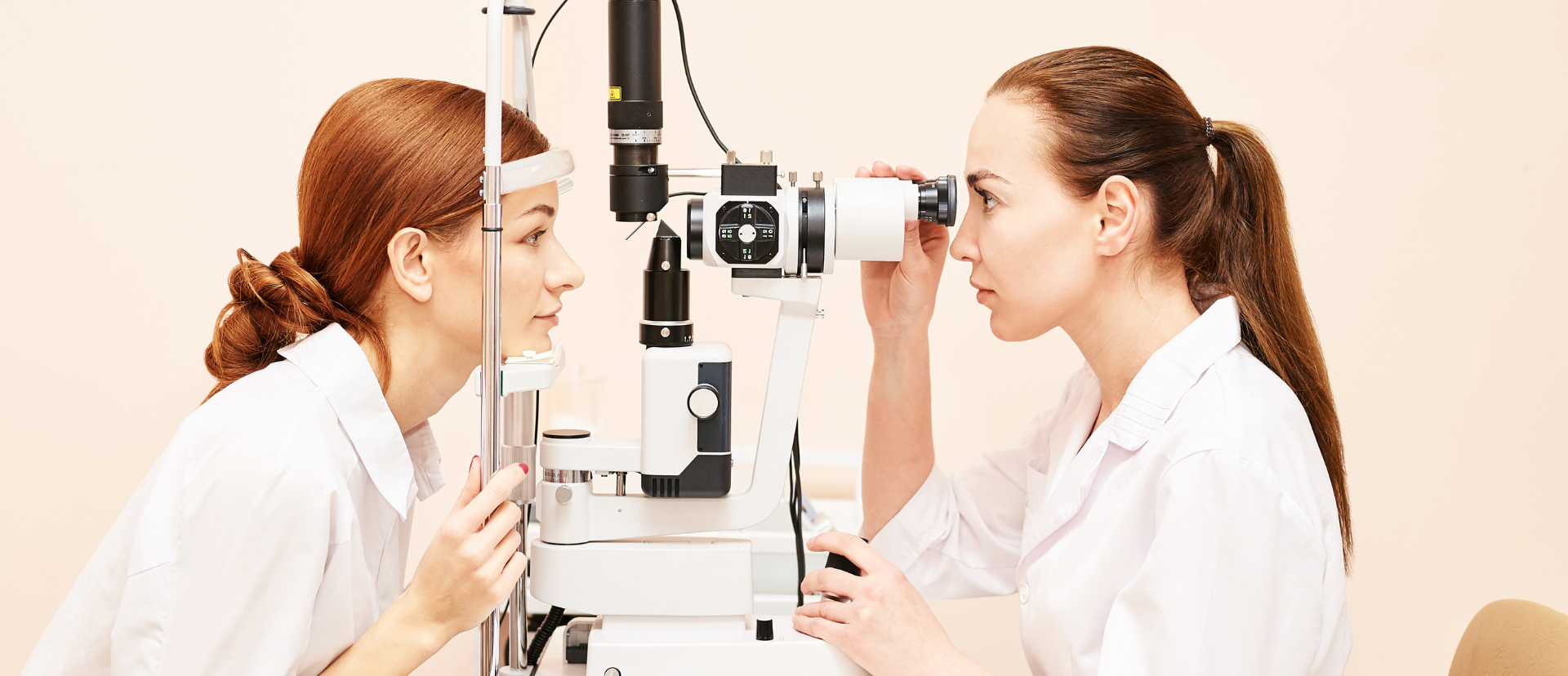 An eye doctor examining a patient's eye with a slit lamp in a medical setting.