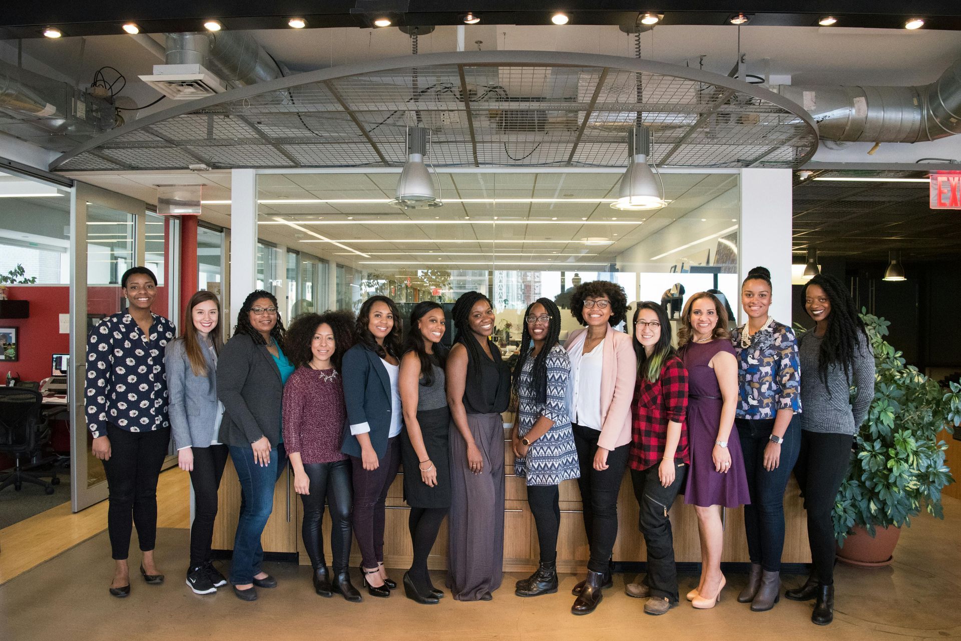 Group of people in an office setting, smiling and posing for a photo.