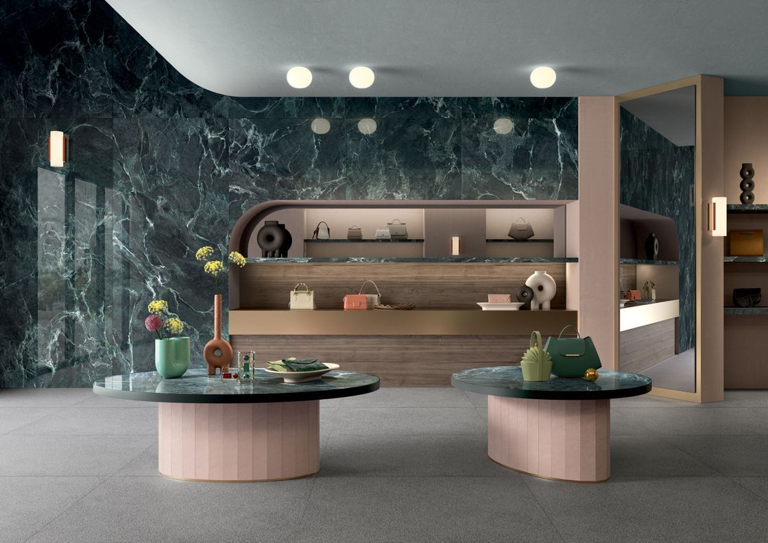 Interieur van een luxe boetiek met marmeren muren, waar handtassen op planken en ronde tafels worden tentoongesteld.