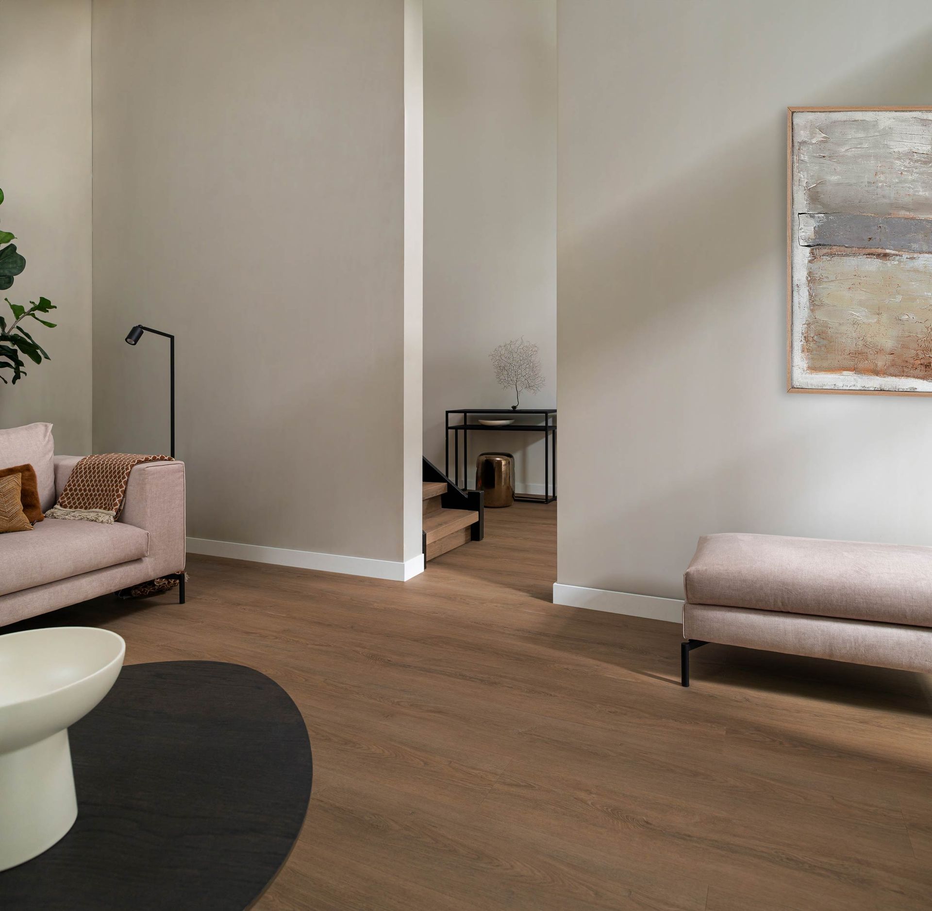 Elegante eetkamer met een grijze muur en vloer met structuurverf. Zwart dressoir, ronde tafel, stoelen en een groot raam.