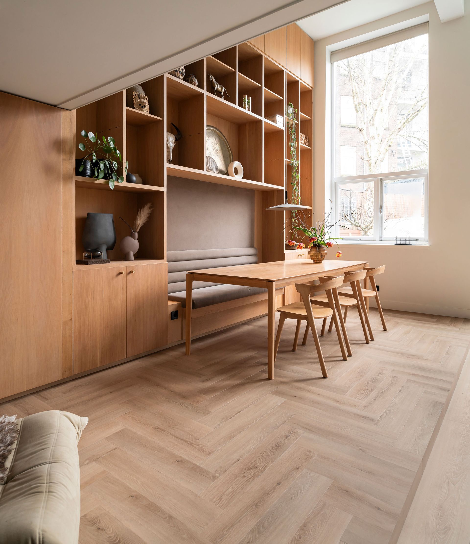 Moderne eetkamer met stenen tegelvloer, grote opening met openslaande deuren en ingebouwde planken.