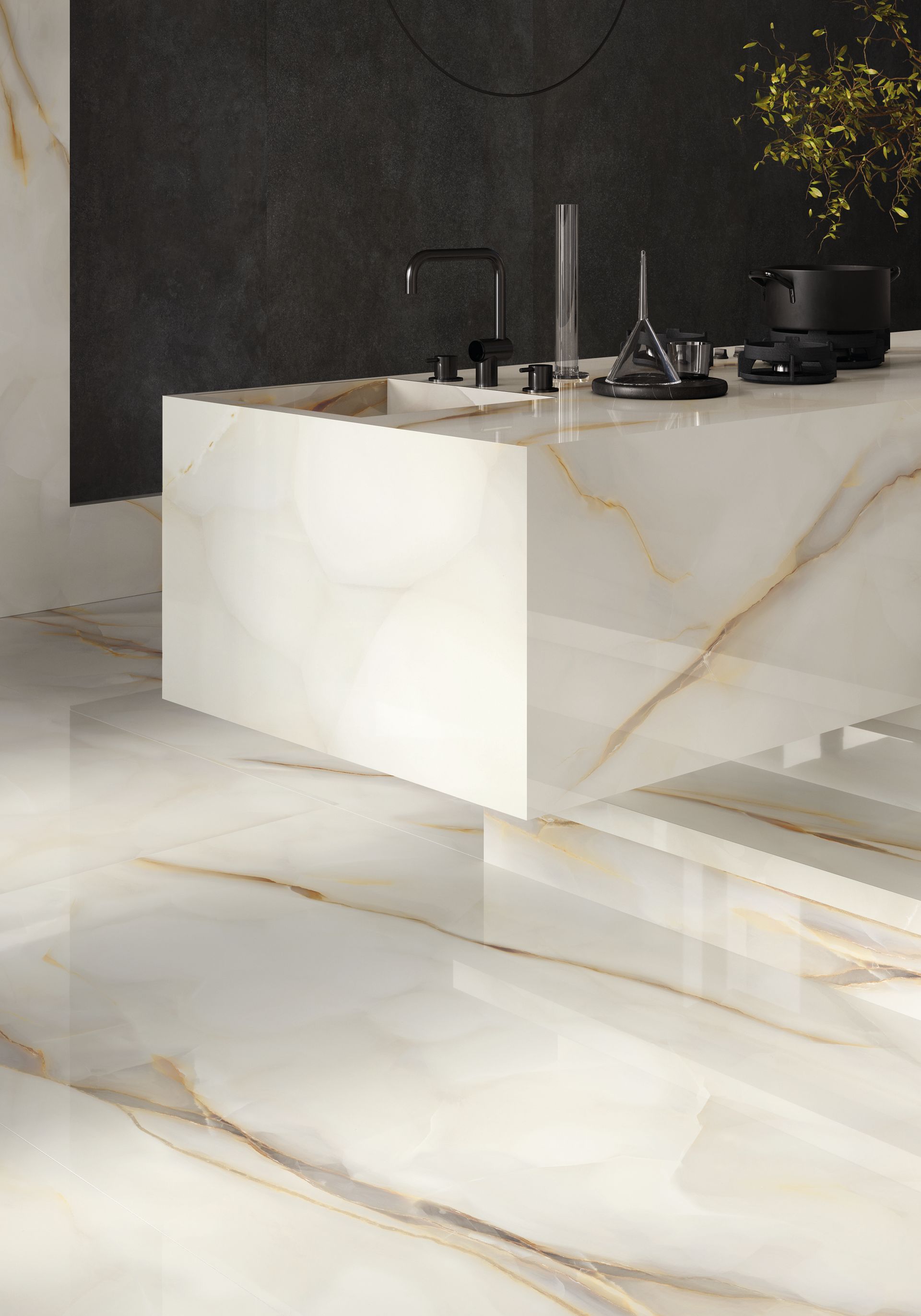 Keukeneiland en -vloer van glanzend wit en goudkleurig marmer, met een donkere achterwand en kookplaat.