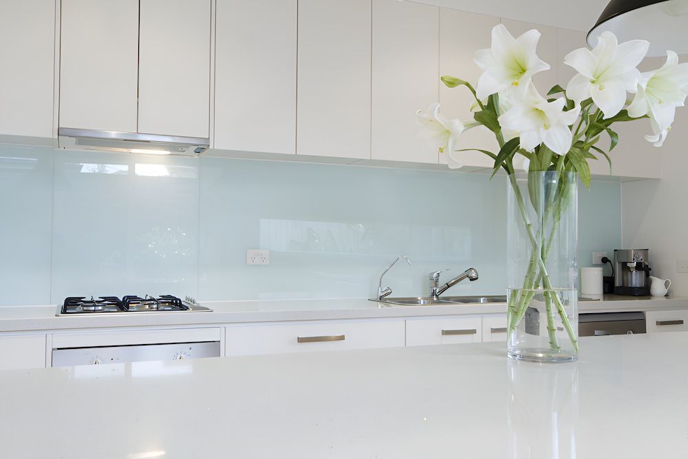 A Kitchen With White Cabinets and a Vase of Flowers on the Counter — All Glass Balustrading Systems in Wetherill Park, NSW