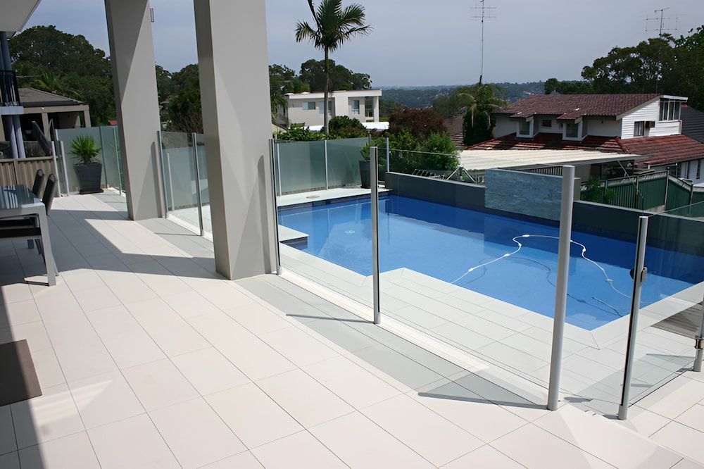 A Large Swimming Pool is Surrounded by a Glass Fence — All Glass Balustrading Systems in Wetherill Park, NSW