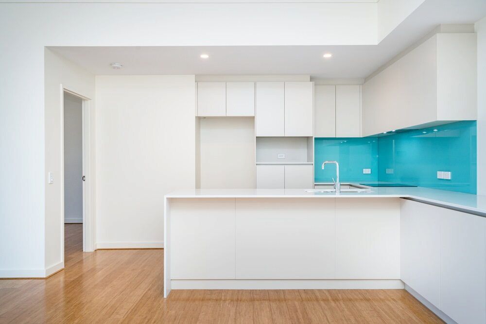 An Empty Kitchen With White Cabinets and a Blue Counter Top — All Glass Balustrading Systems in Wetherill Park, NSW