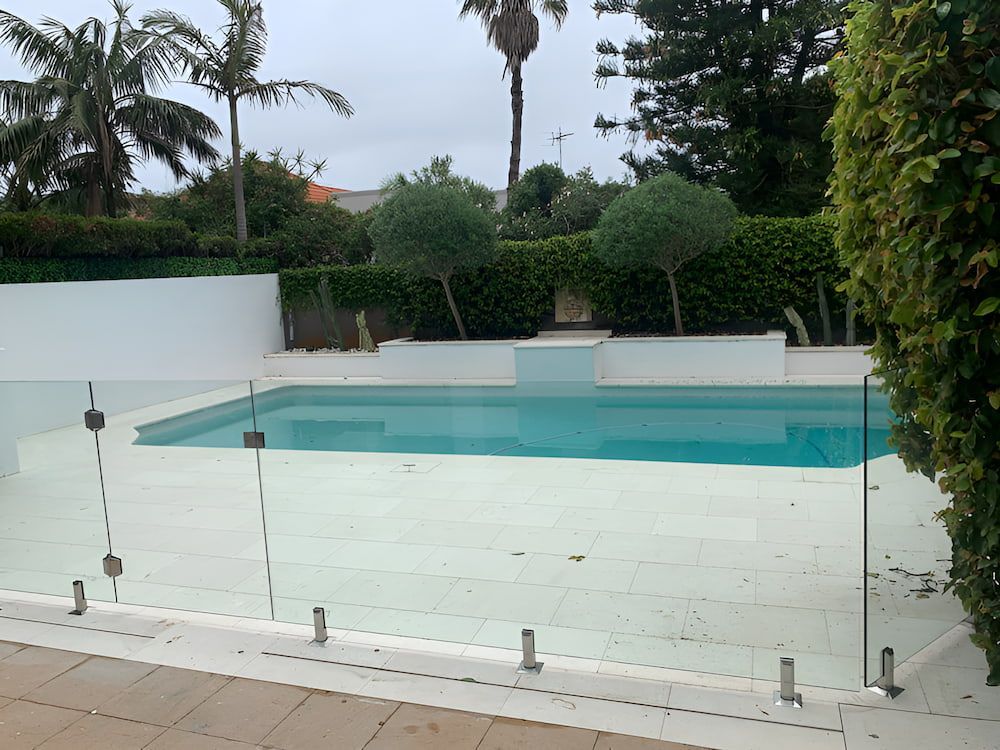 A Swimming Pool With a Glass Fence Around It — All Glass Balustrading Systems in Wetherill Park, NSW