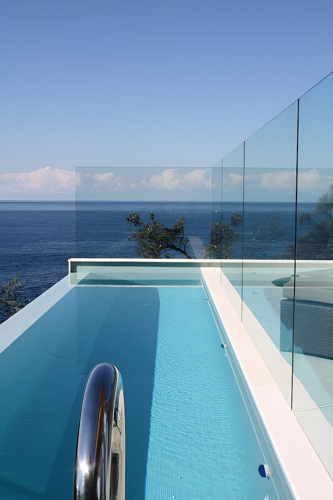 A Swimming Pool With a Glass Railing Overlooking the Ocean — All Glass Balustrading Systems in Wetherill Park, NSW