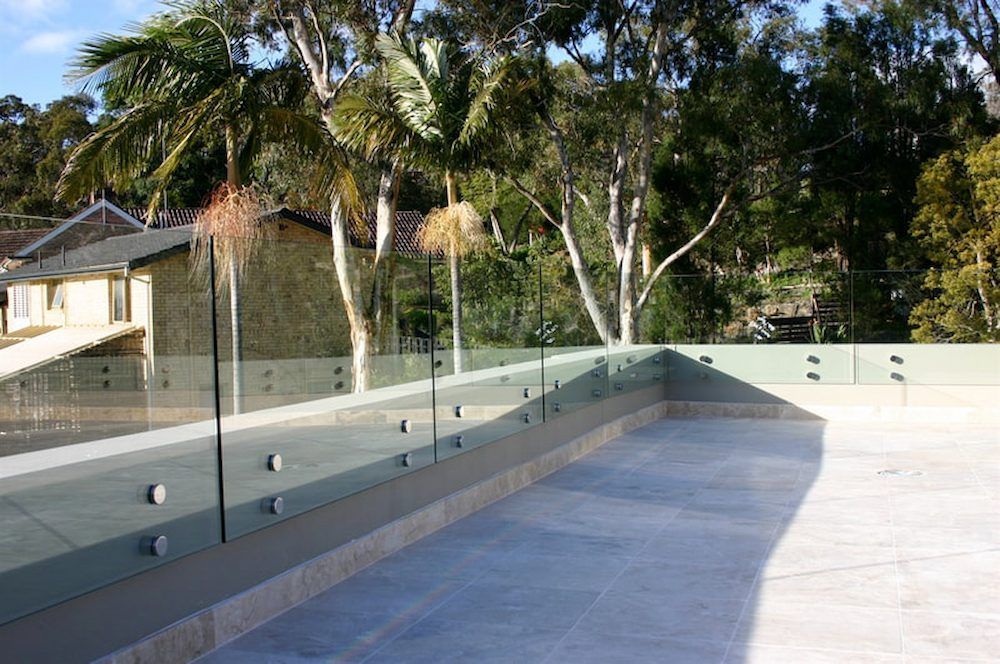 A Balcony With a Glass Railing and Trees in the Background — All Glass Balustrading Systems in Bondi, NSW