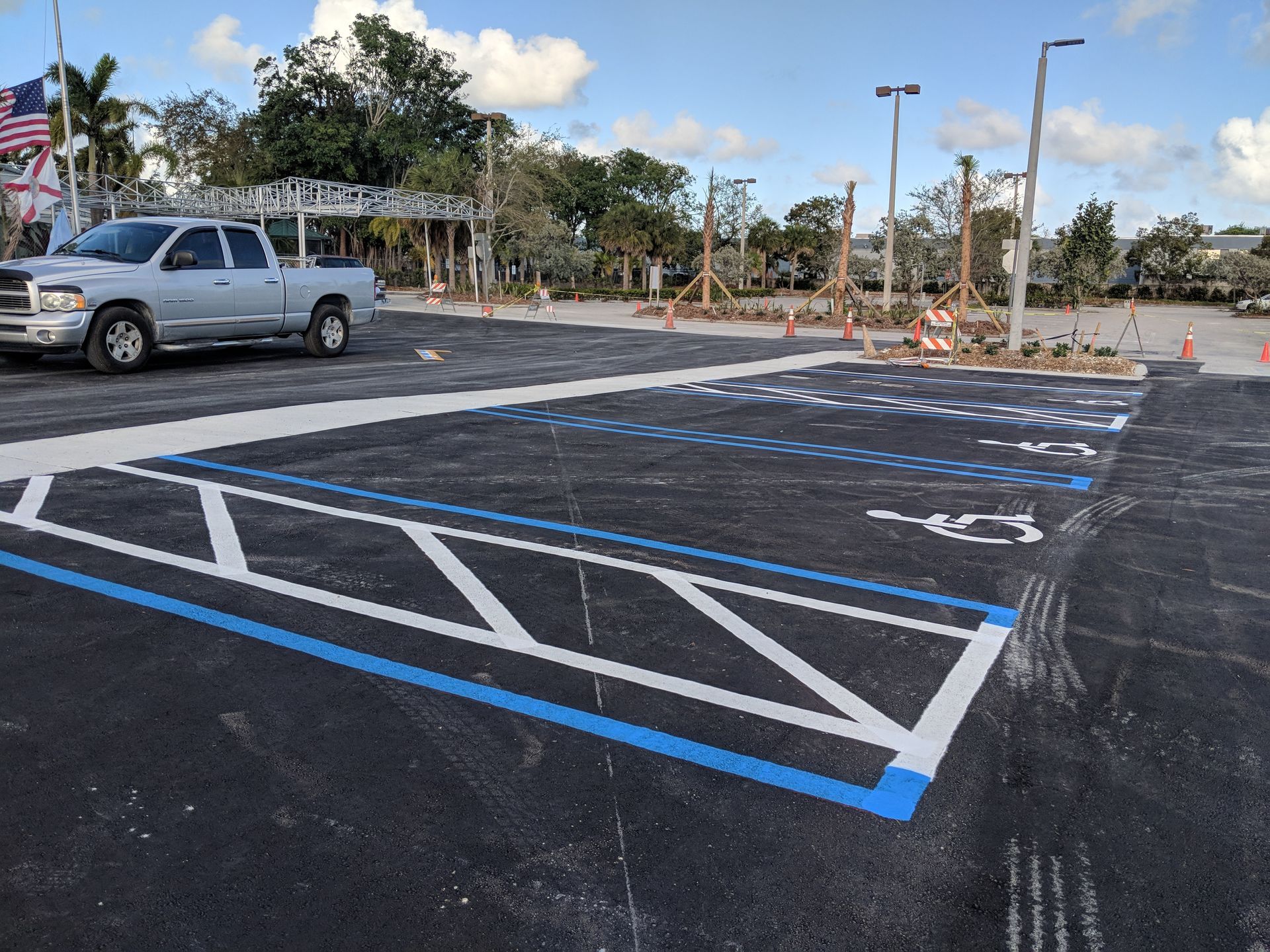 An outdoor parking lot with newly painted, blue-bordered, handicap-accessible parking spaces.