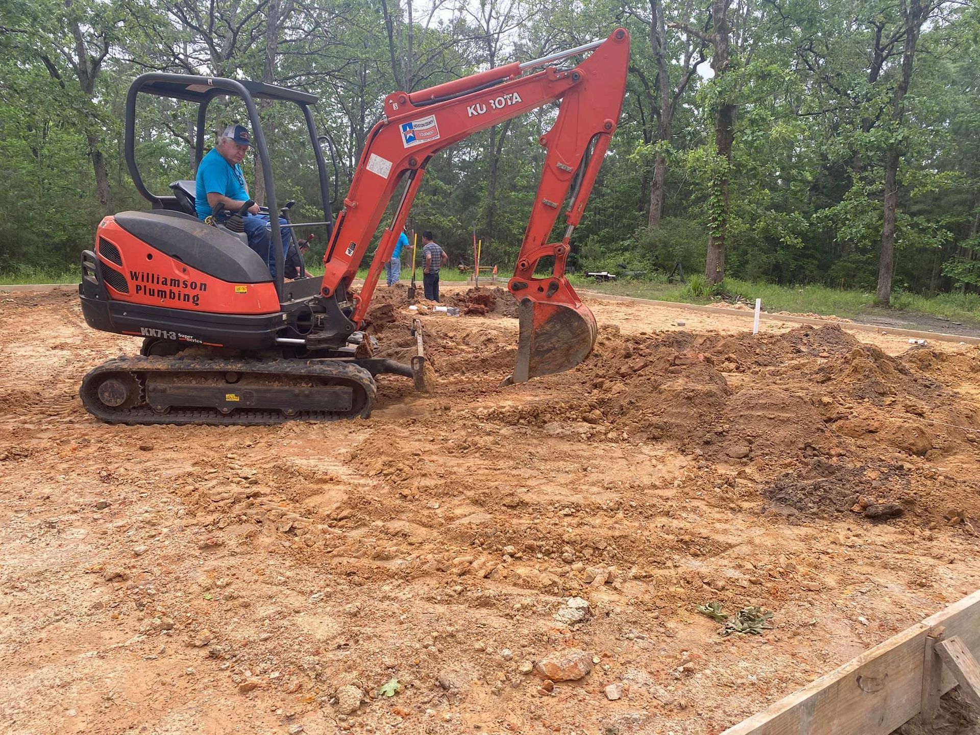 Orange excavator digging dirt on a construction site. Man in cab.