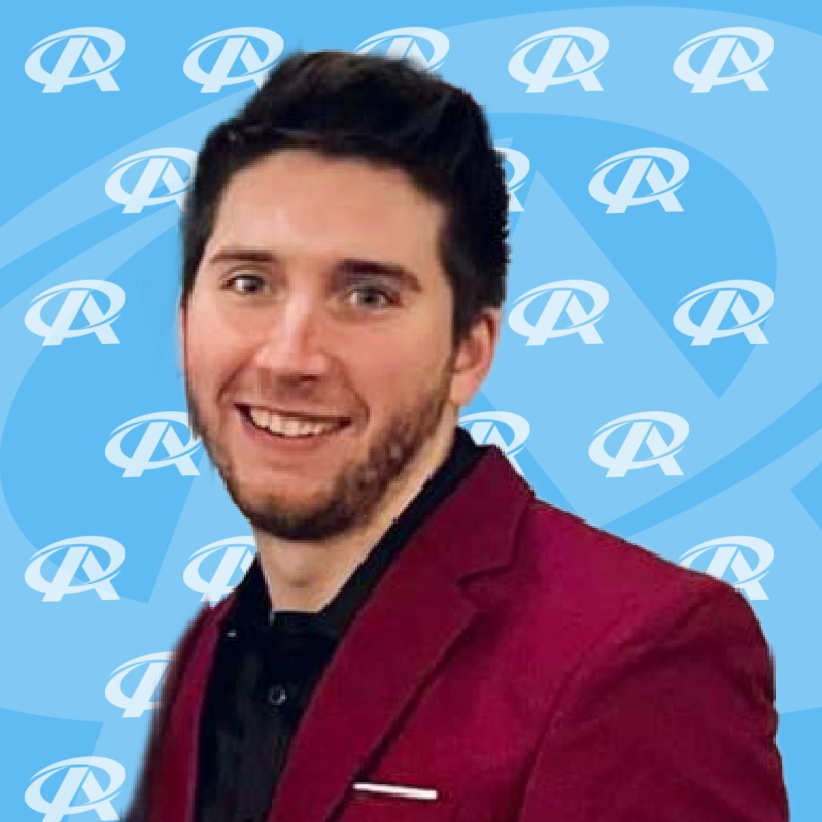 A man in a red suit is smiling in front of a blue background
