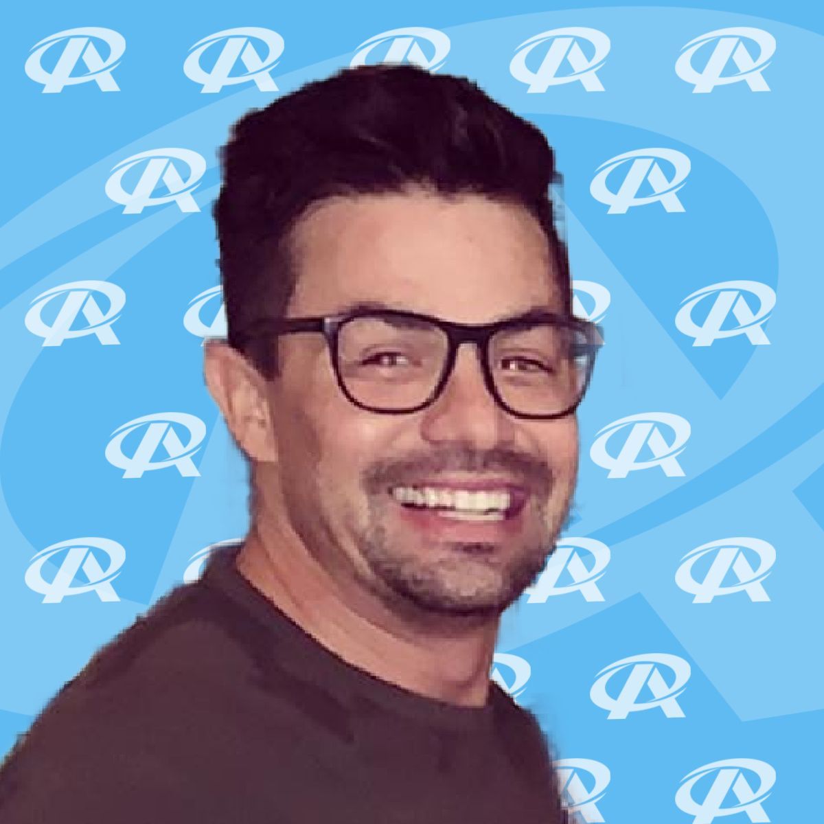 A man wearing glasses is smiling in front of a blue background