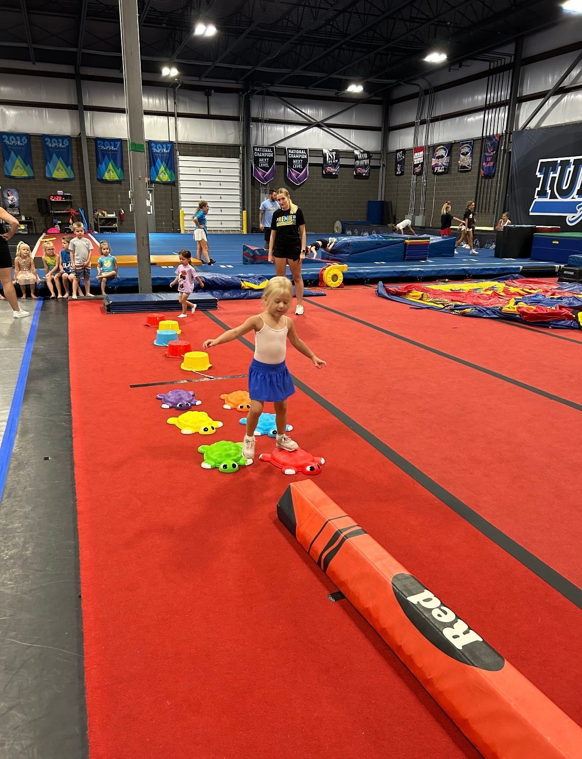 A little girl is walking on a balance beam in a gym.