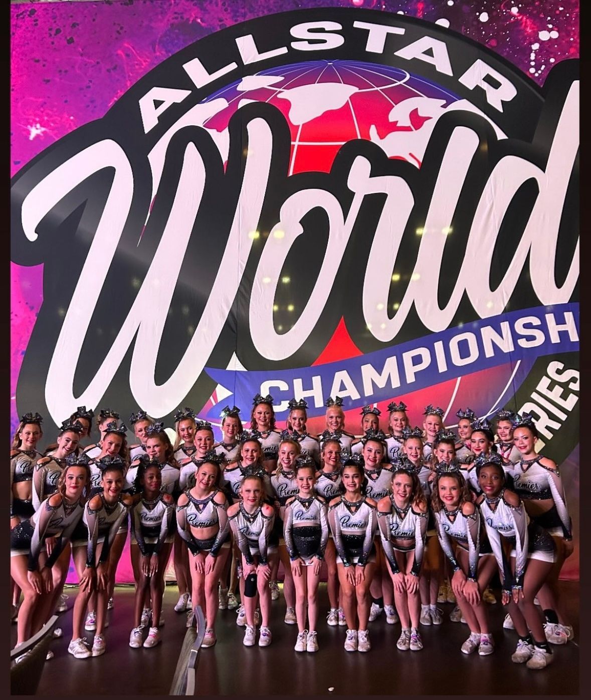 A group of cheerleaders are posing for a picture in front of an all star world championship logo