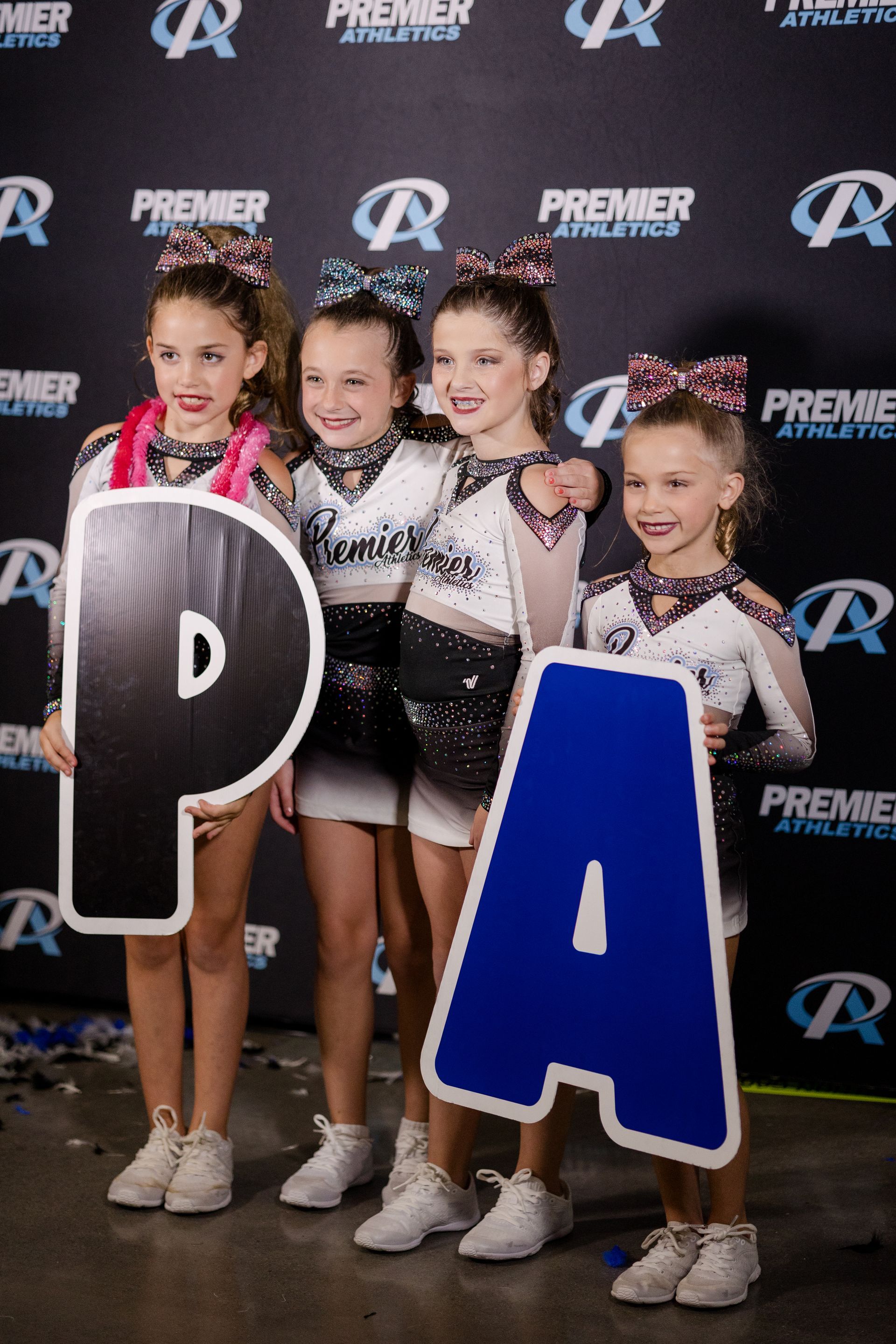 A group of cheerleaders are posing for a picture while holding large letters.