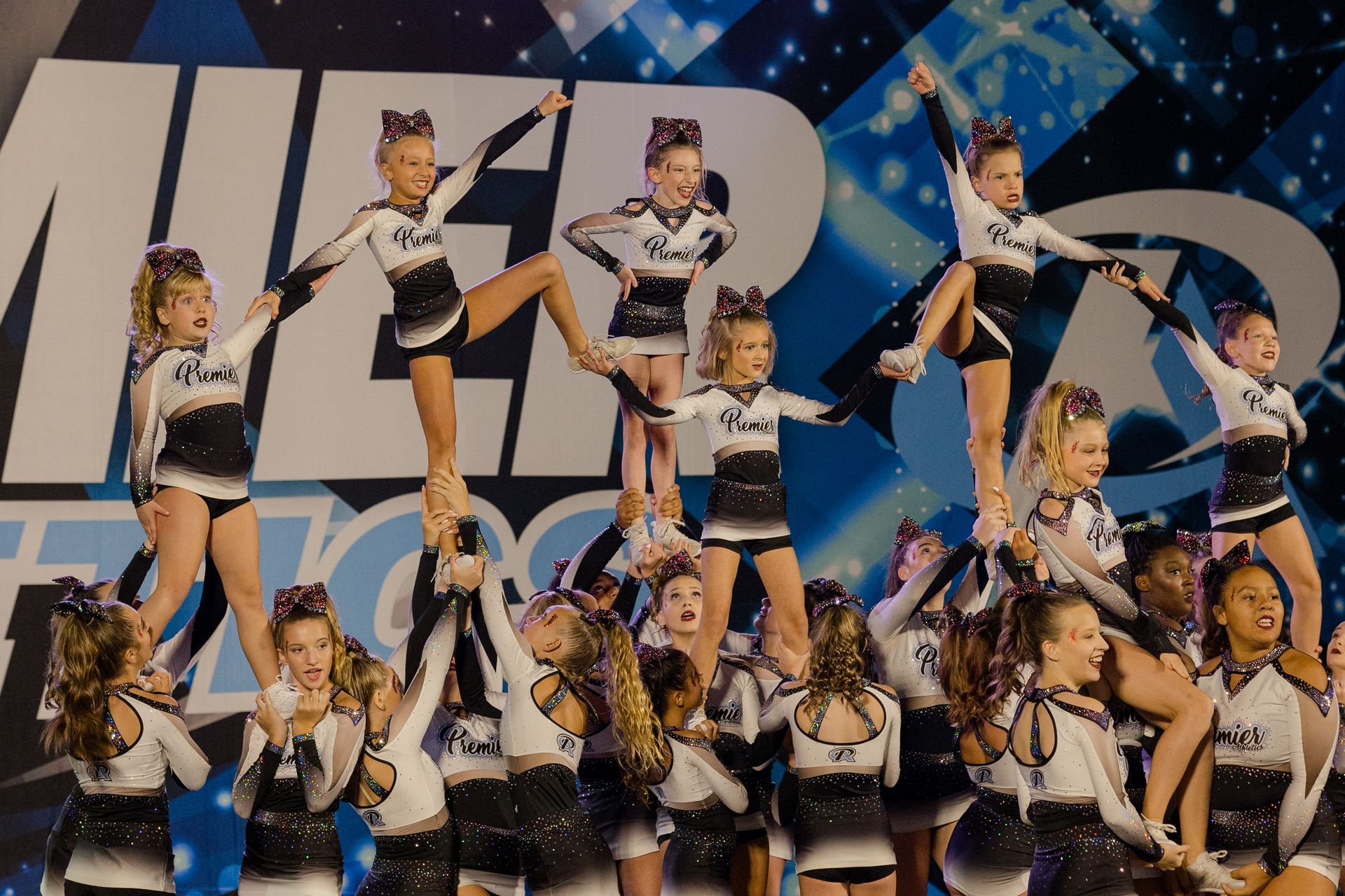 A group of cheerleaders are performing in front of a large letter m.