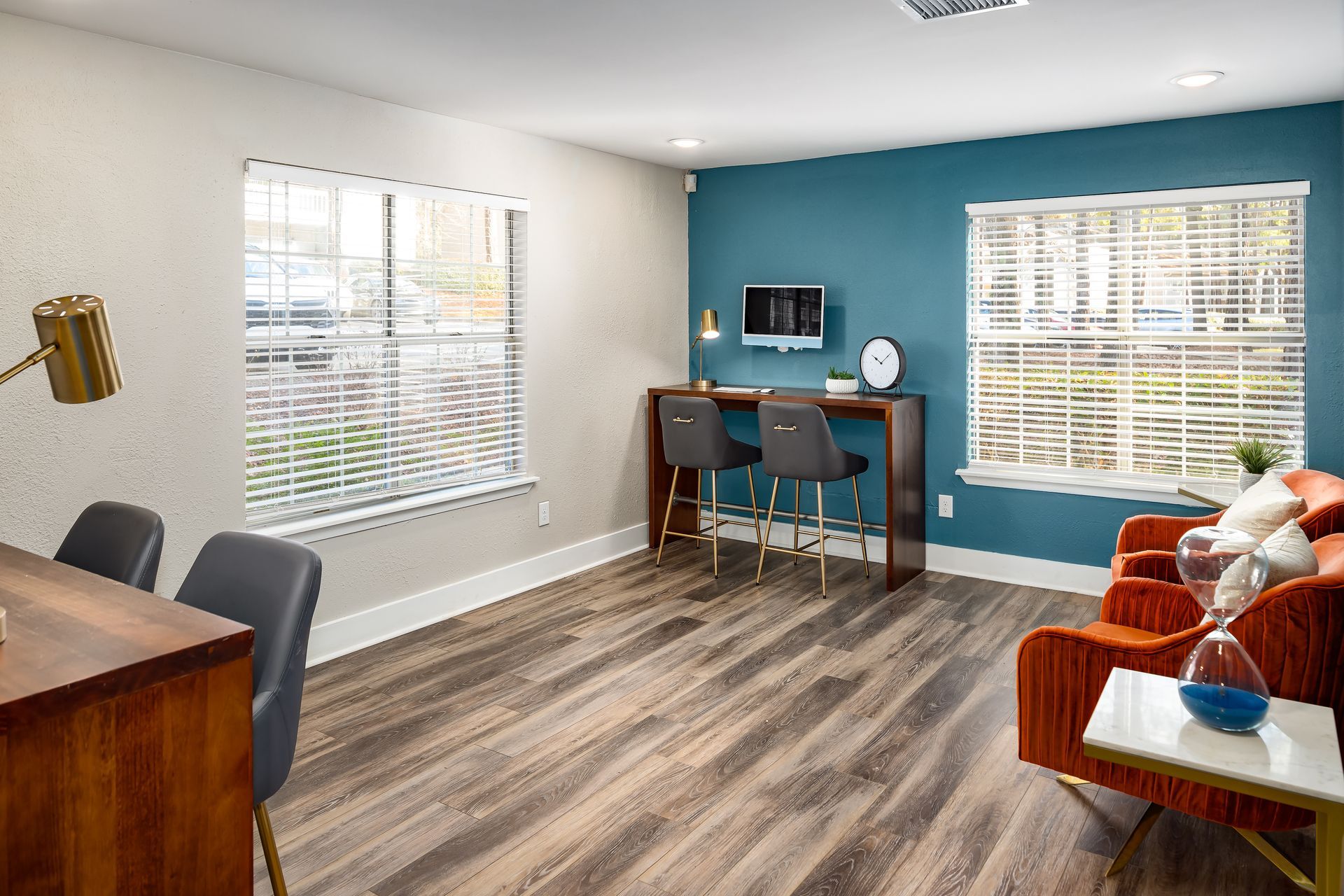 A living room with hardwood floors , a couch , chairs , a desk and a television.