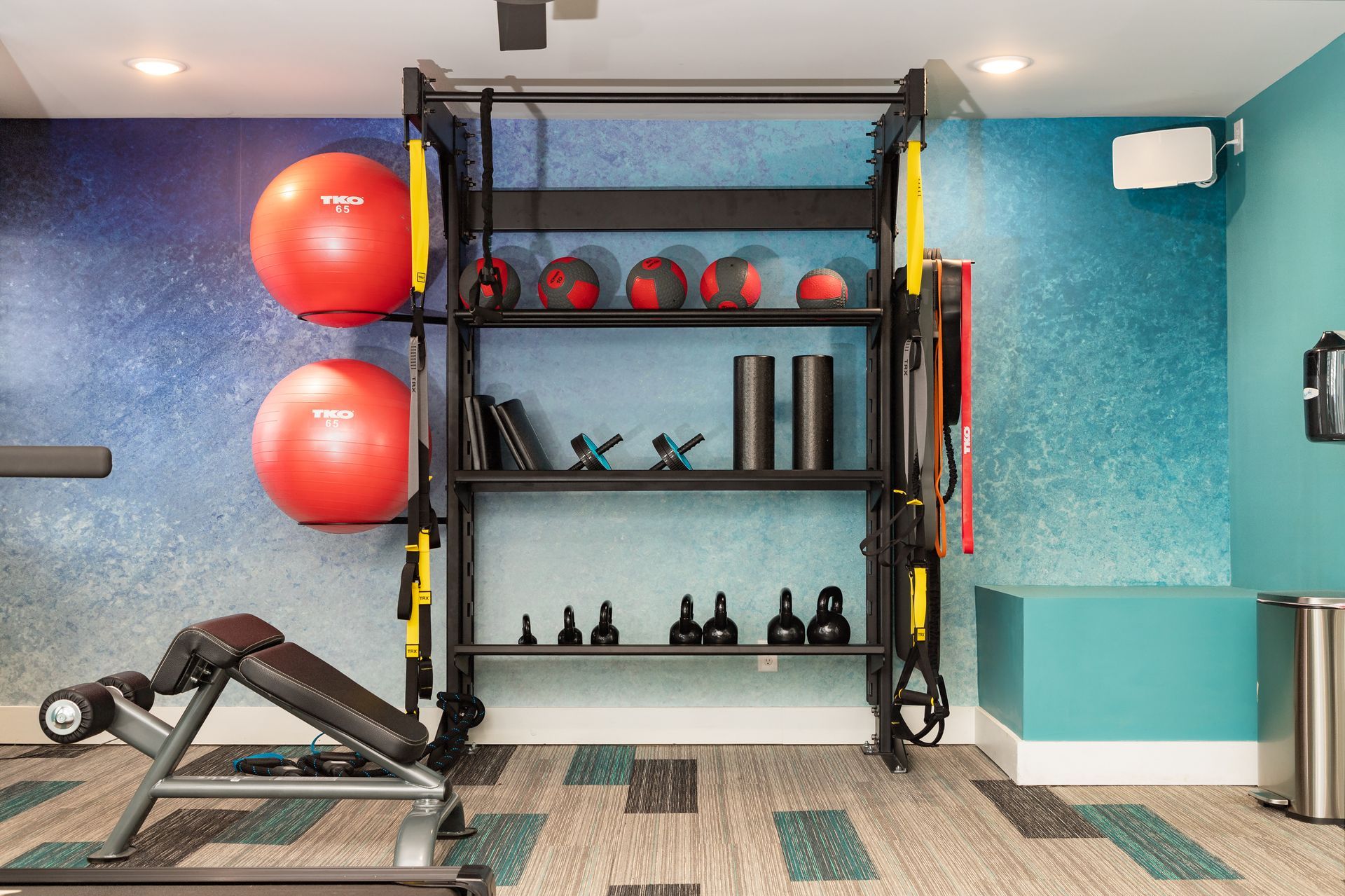 A gym with a treadmill , exercise balls , and dumbbells.