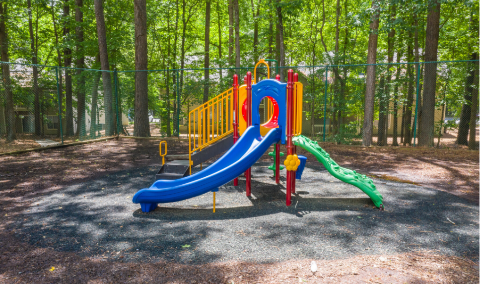 A colorful playground in the middle of a forest at The Mark at Riverdale.
