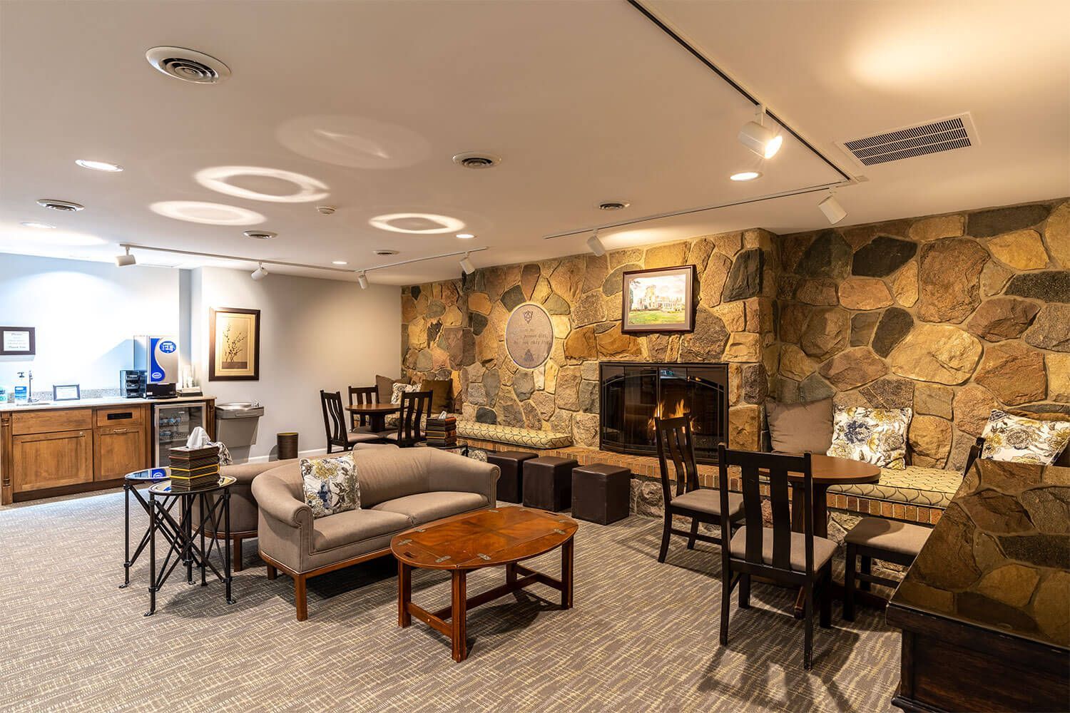 Cozy lounge with stone fireplace, seating areas, and coffee station.