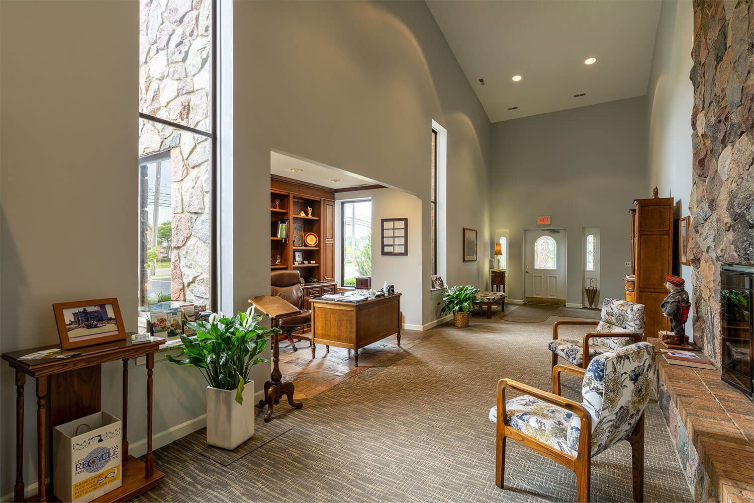 Lobby with stone wall, high ceilings, seating, and a desk. A window provides natural light.