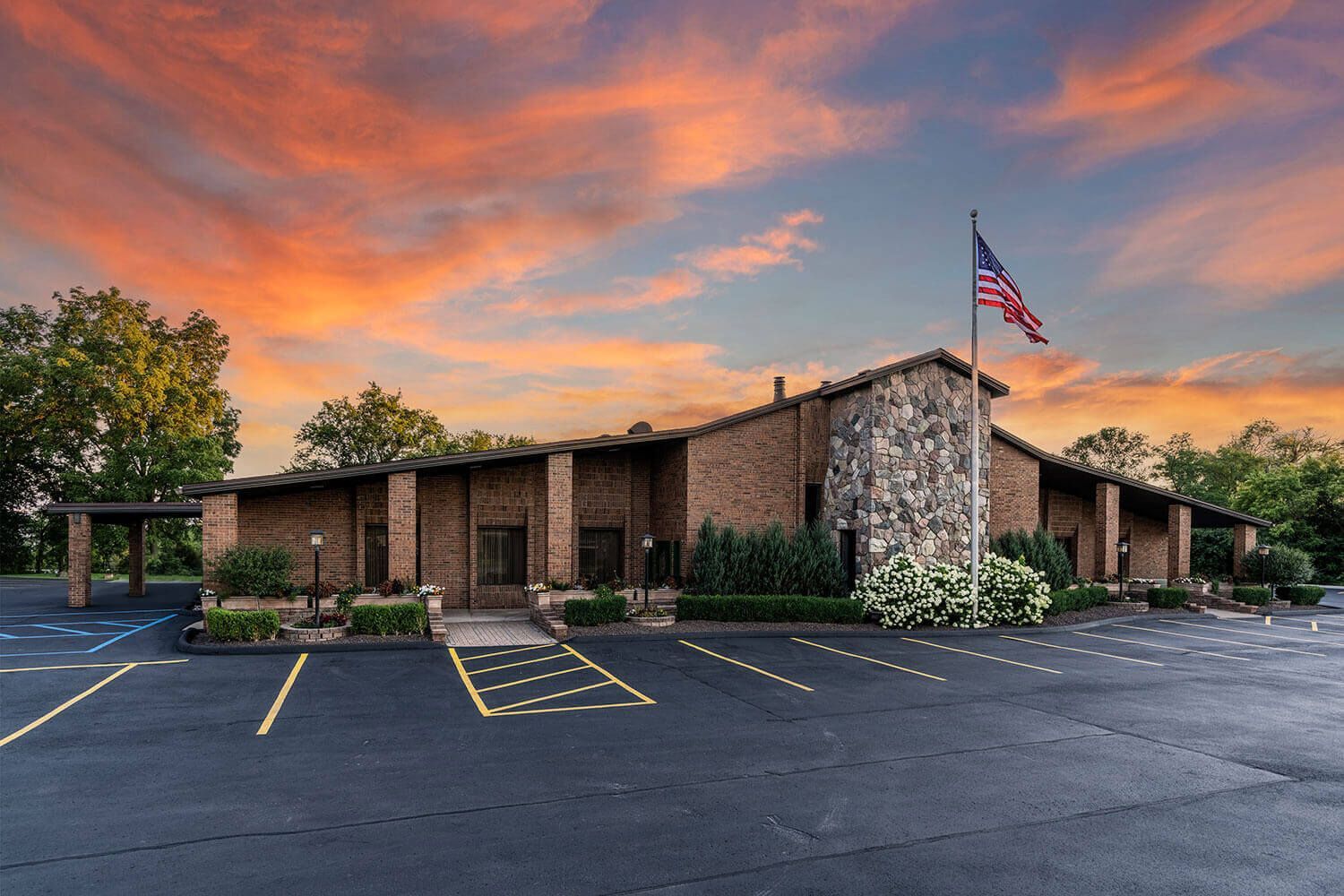Funeral home building with American flag against a sunset sky.