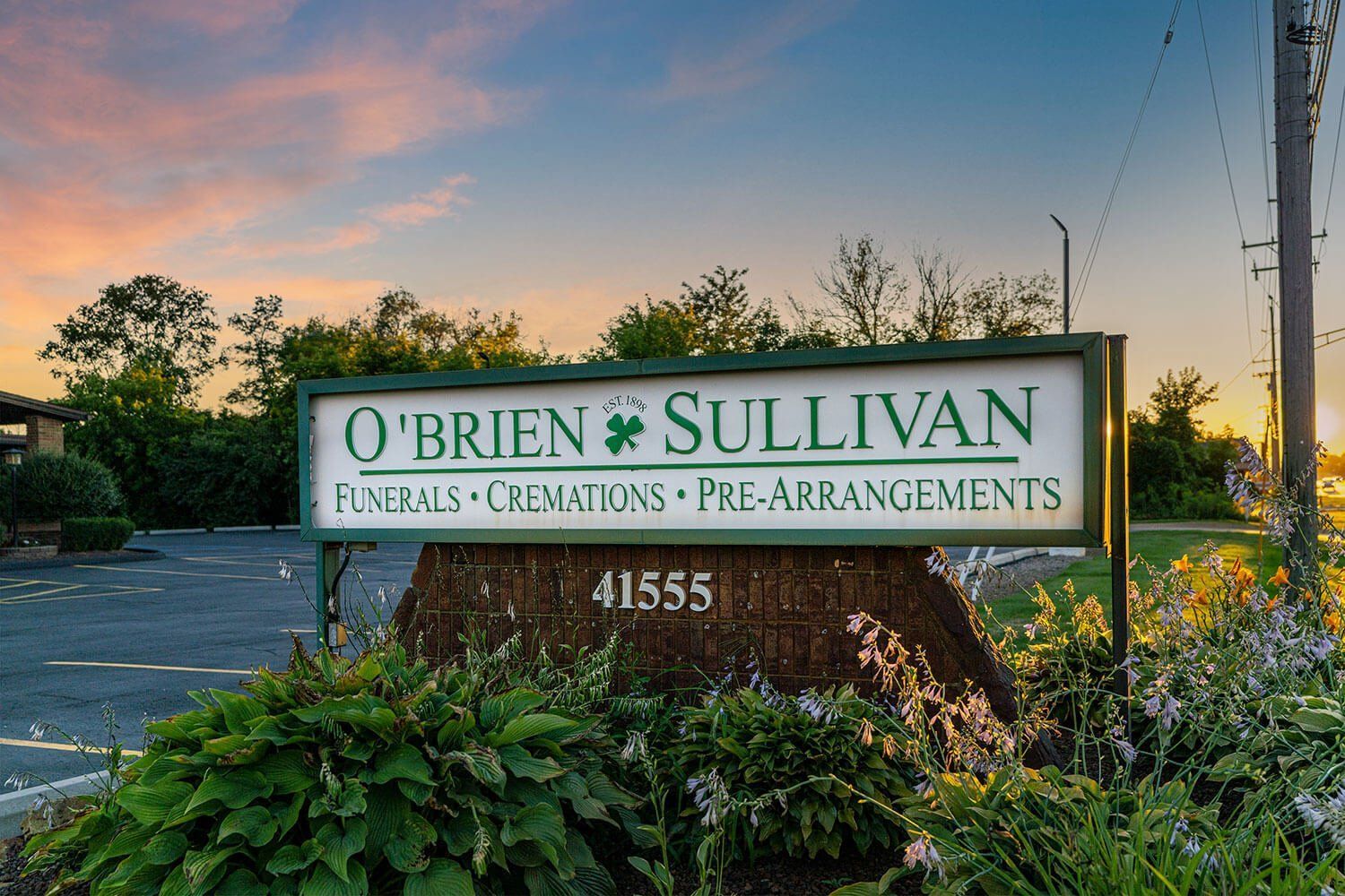 Sign for O'Brien Sullivan funeral home with green and white lettering, address 41555, dusk setting.