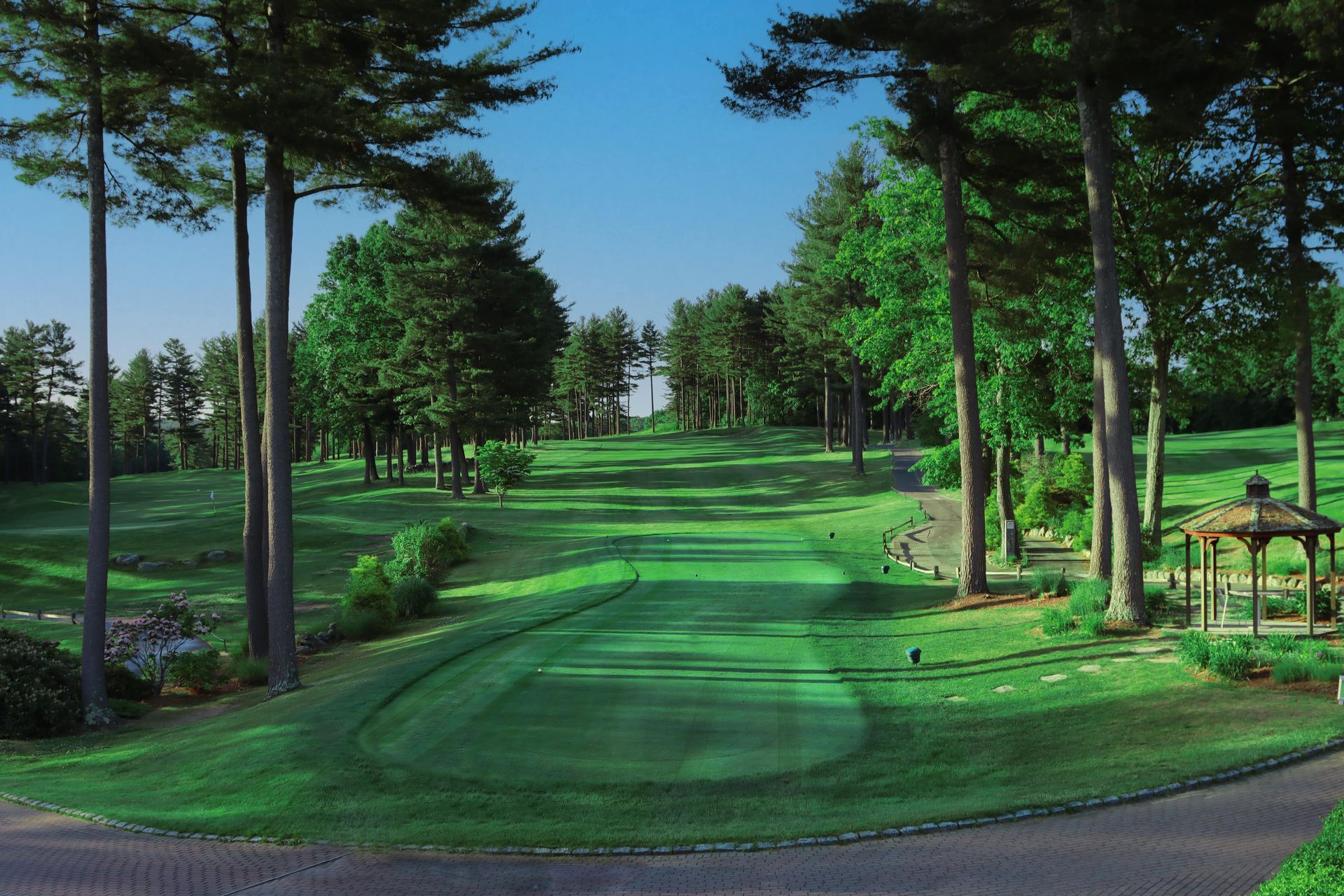 A golf course surrounded by trees and a gazebo