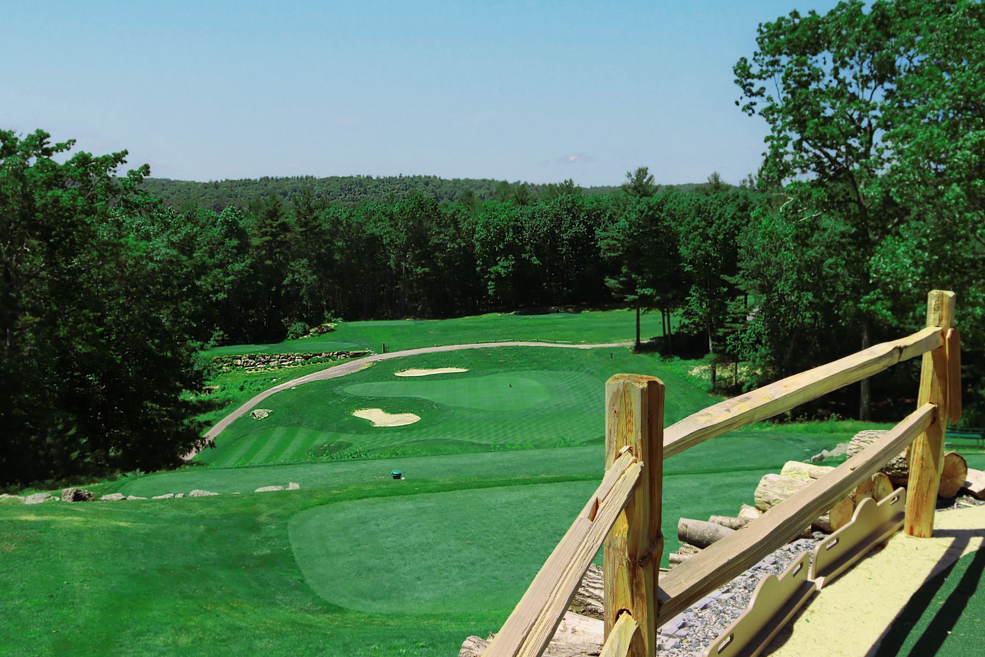 A view of a golf course with a wooden fence in the foreground