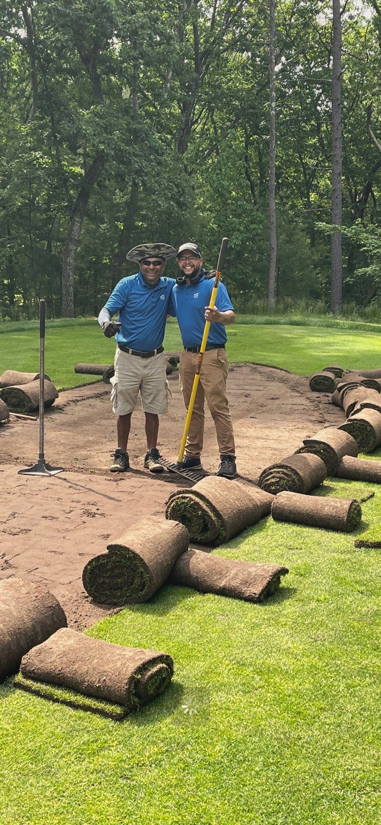 Two men are standing next to each other on a lush green field.