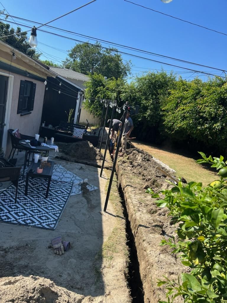 A Man is Digging a Hole in the Ground in Front of a House