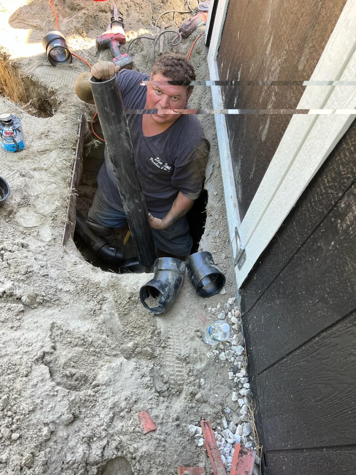 A Man is Kneeling in the Dirt Holding a Pipe