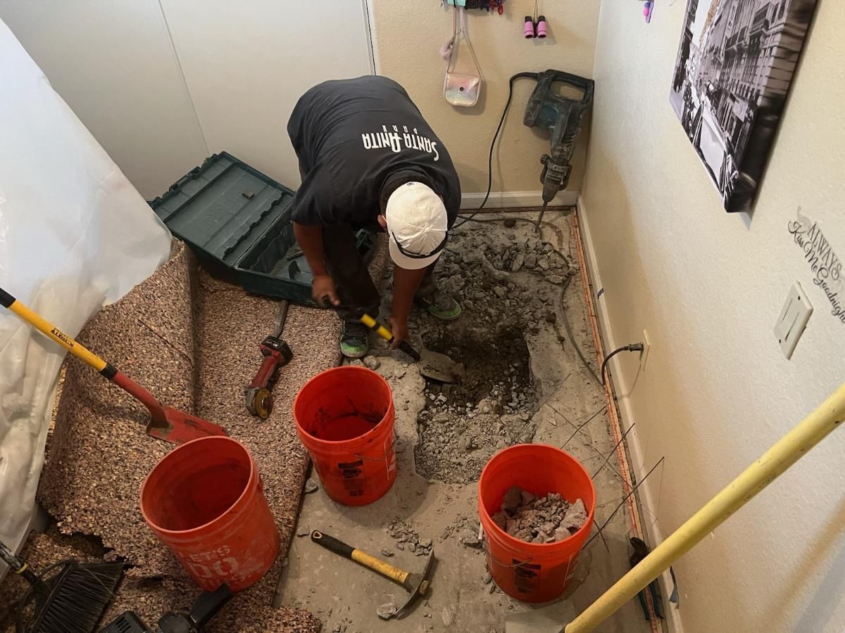 A Man is Working on a Bathroom Floor With Buckets and Tools