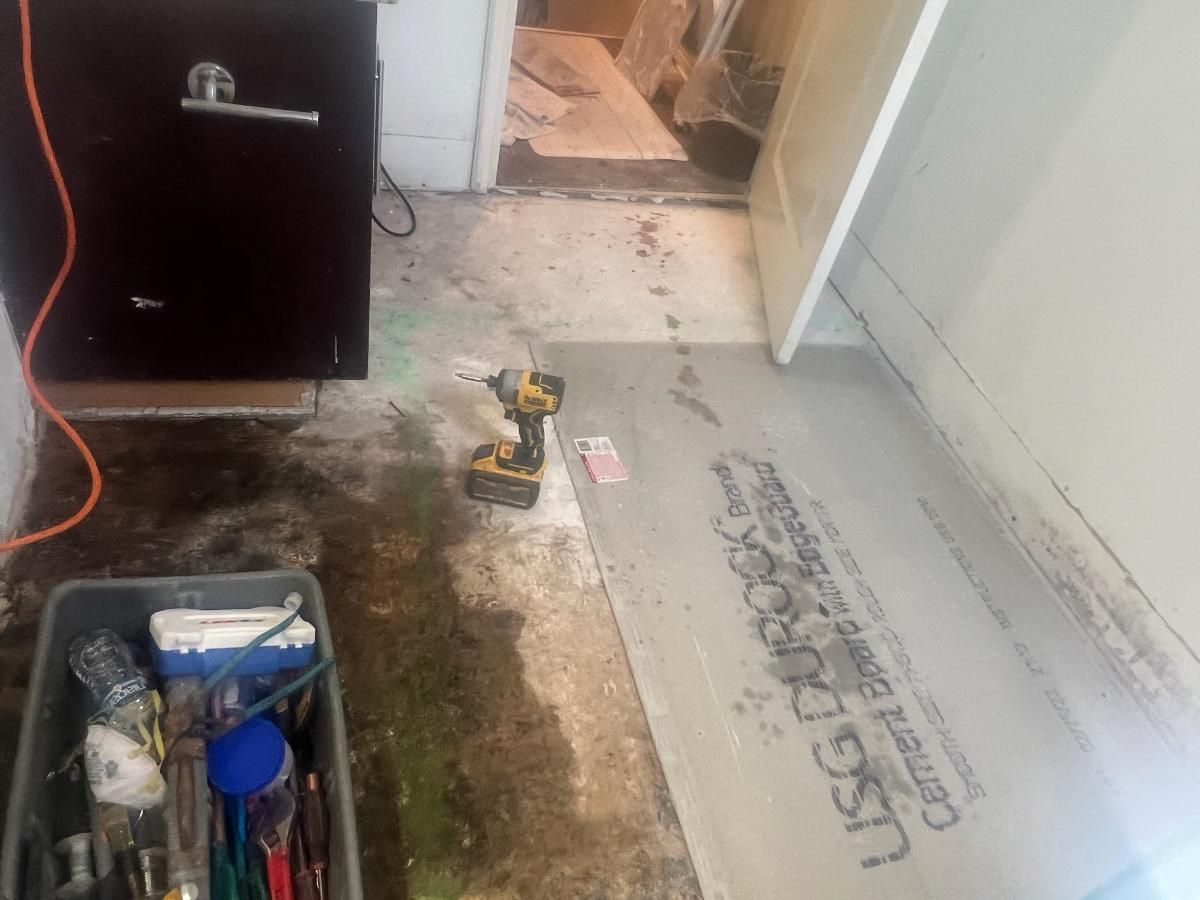 A Drill is Sitting on the Floor of a Room Next to a Box of Tools