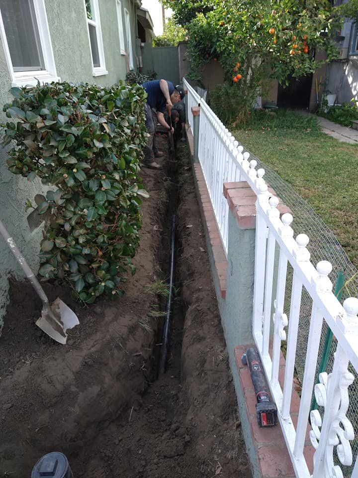 A Man is Digging a Hole in the Ground Next to a White Fence