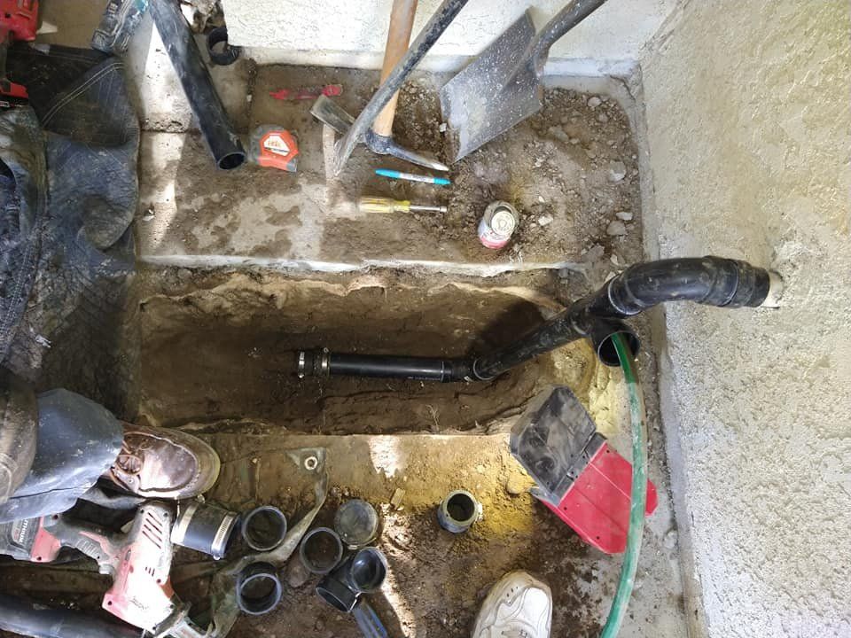 A Person is Working on a Pipe in a Hole in the Ground