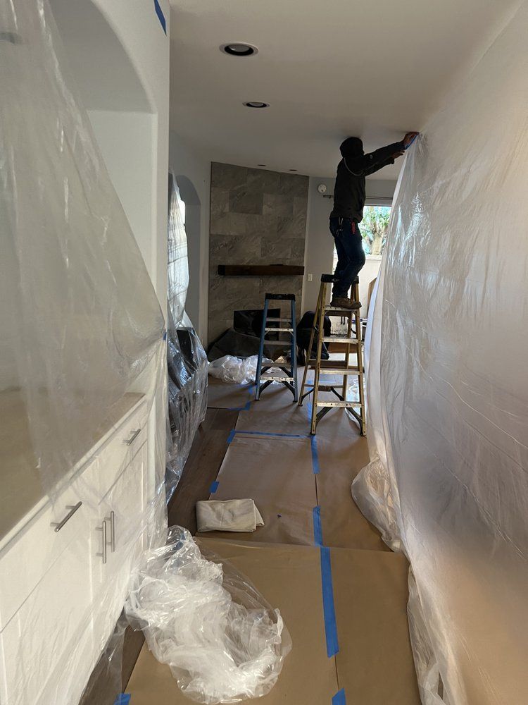 A Man is Standing on a Ladder Painting a Wall