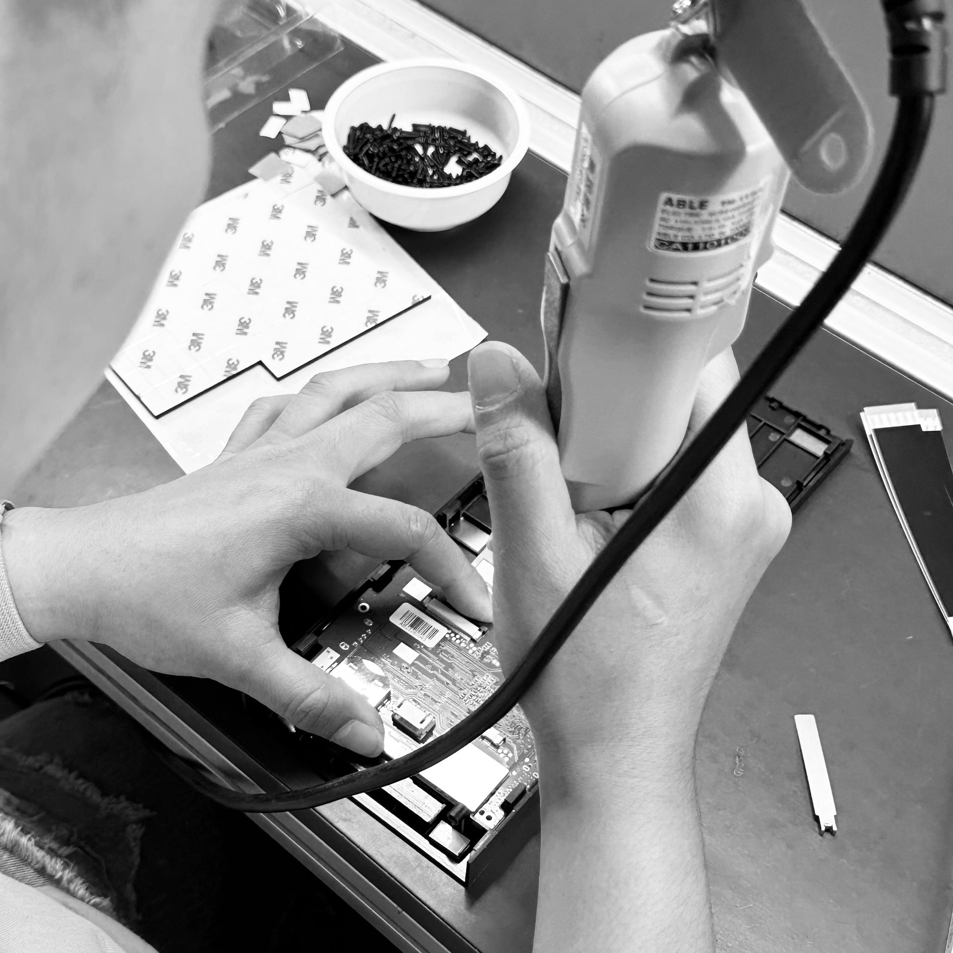 A black and white photo of a person assembling a product